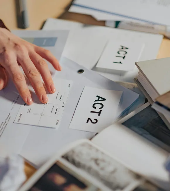 A person holds a paper displaying the text Act 2, indicating a scene or segment in a performance or script.
